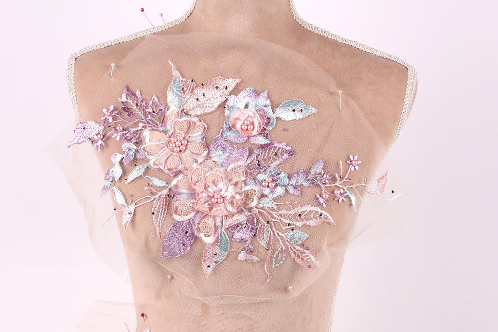 A mannequin torso with a delicate floral embroidered on it, featuring a variety of pink and purple flowers and leaves.