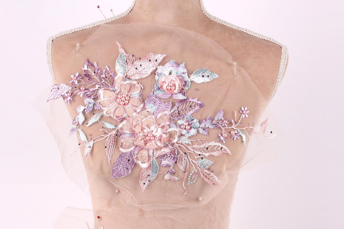 A mannequin torso with a delicate floral embroidered on it, featuring a variety of pink and purple flowers and leaves.