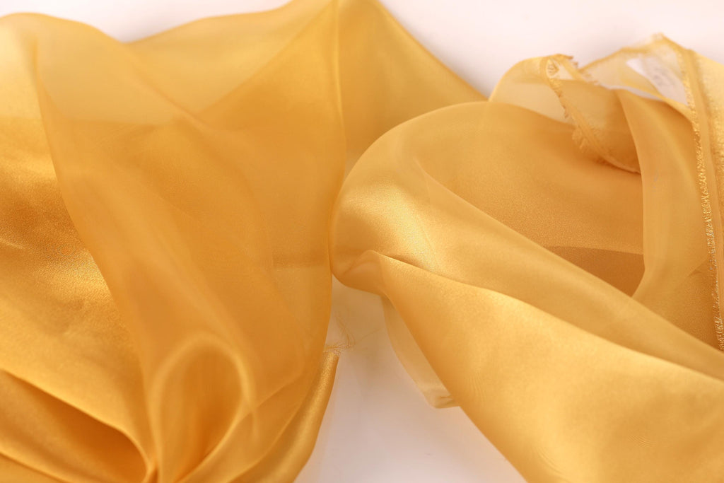 a close-up view of a piece of yellow fabric, possibly silk or chiffon, with a soft, flowing texture.