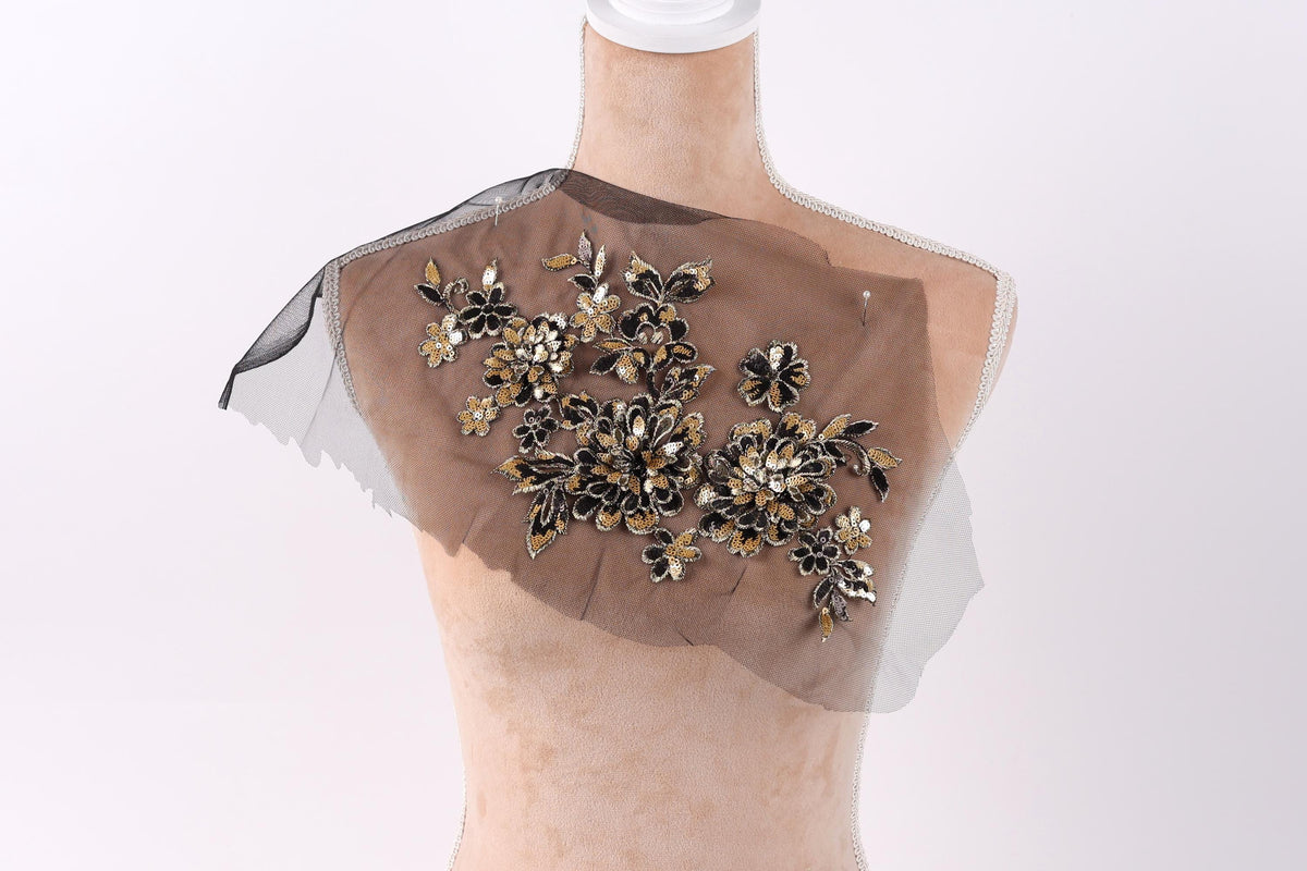 A mannequin wearing a dress with a decorative floral pattern on the shoulder.