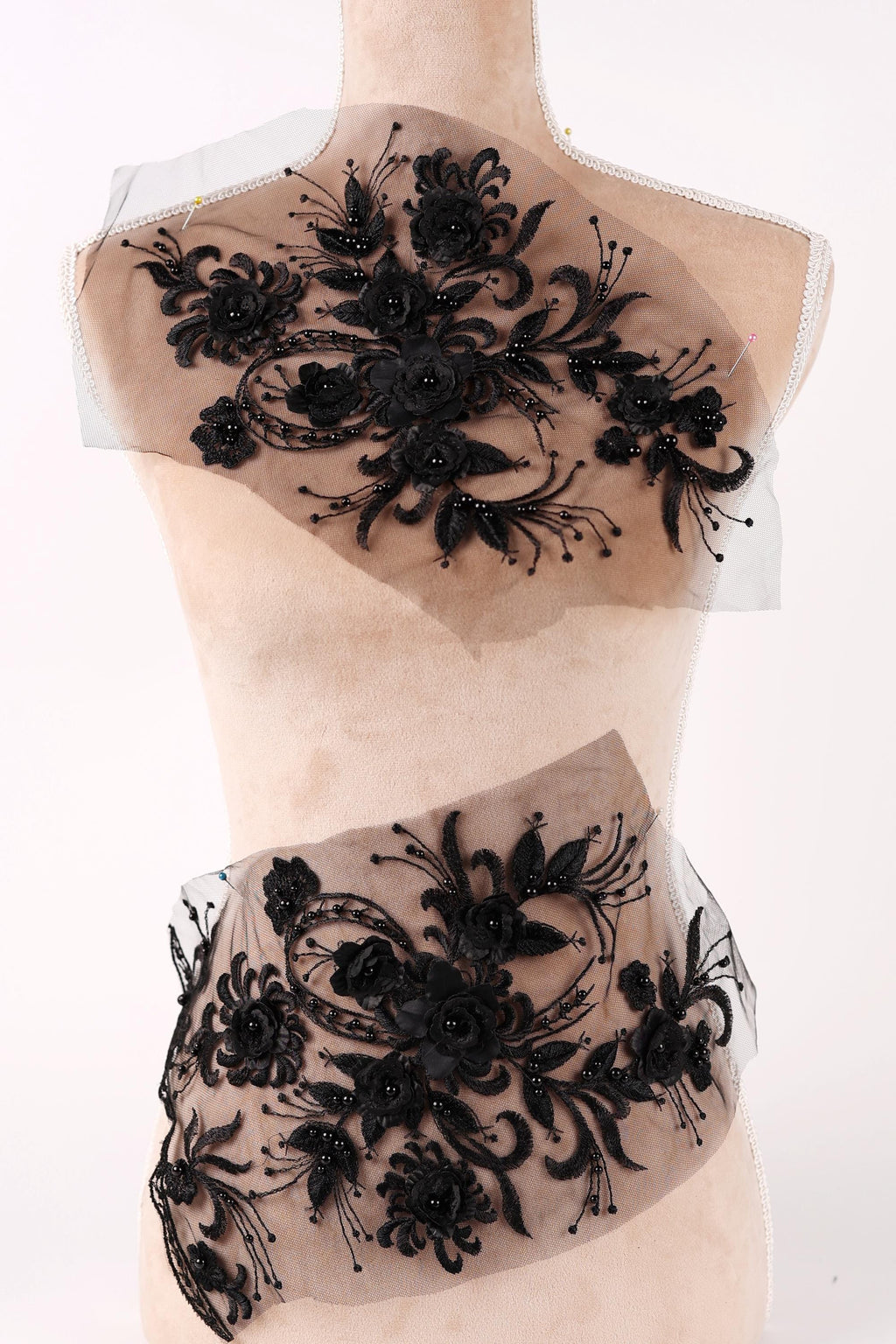 A mannequin wearing a dress with a black floral pattern on the bodice and a sheer, lace-like skirt.