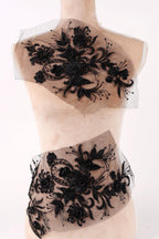 A mannequin wearing a dress with a black floral pattern on the bodice and a sheer, lace-like skirt.