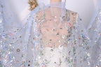 a close-up view of a delicate, sheer fabric with a floral pattern. The fabric appears to be made of sheer material, giving it a delicate and airy appearance. The intricate floral design is visible on the fabric, adding a touch of elegance and sophistication to the overall look.