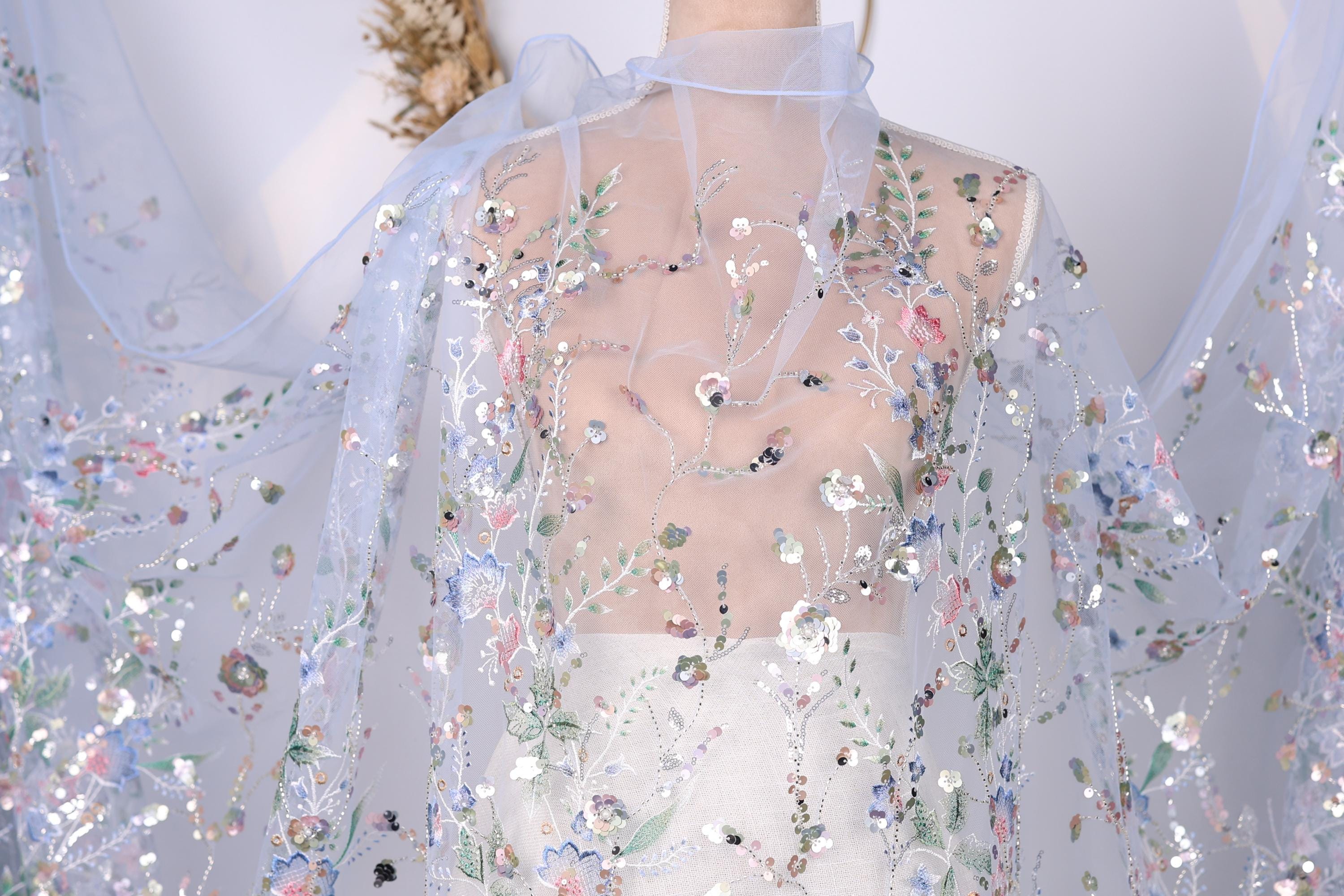 a close-up view of a delicate, sheer fabric with a floral pattern. The fabric appears to be made of sheer material, giving it a delicate and airy appearance. The intricate floral design is visible on the fabric, adding a touch of elegance and sophistication to the overall look.