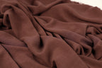 A close-up view of a brown fabric, possibly a piece of clothing or textile, with a crumpled and wrinkled texture.