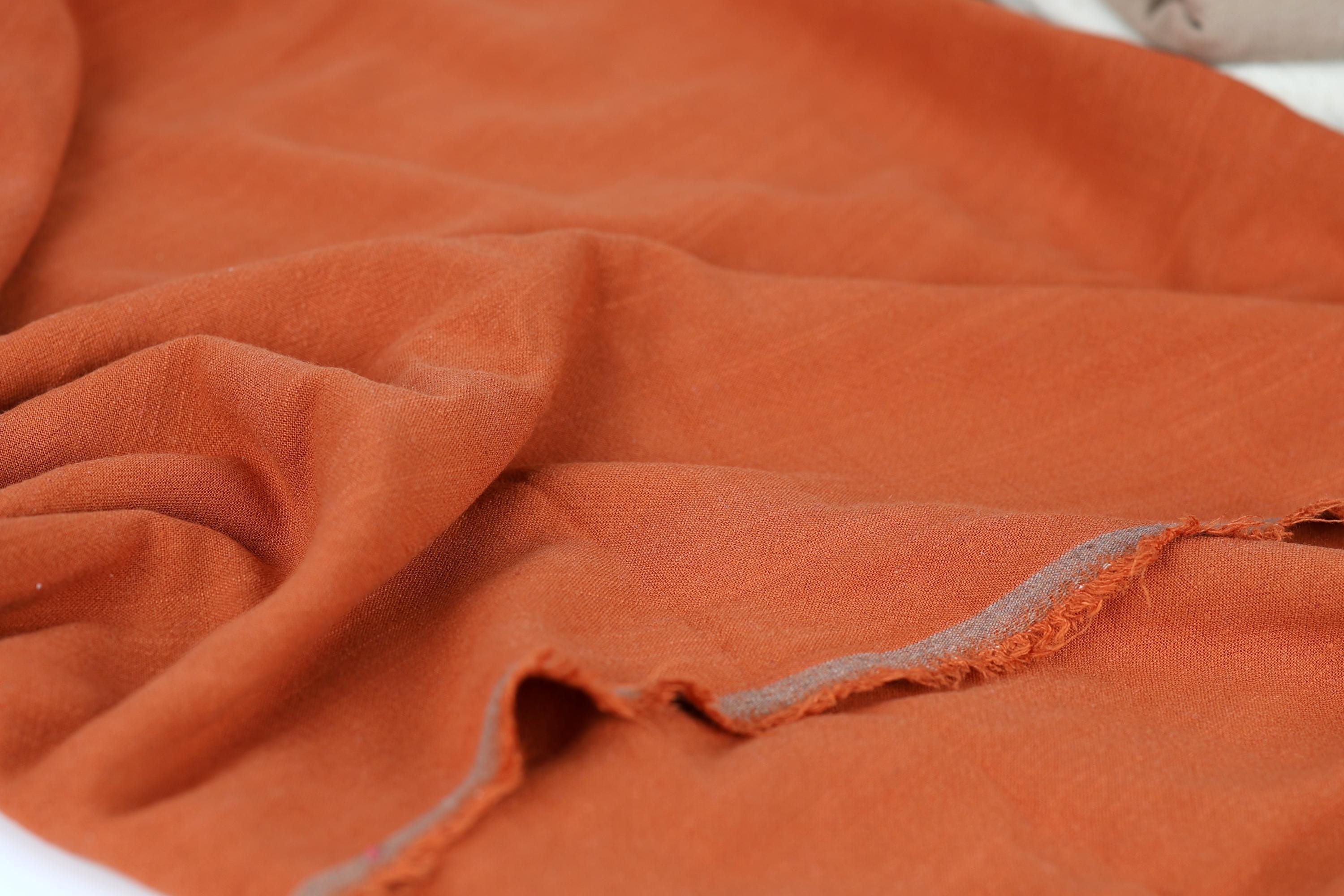 a close-up view of a crumpled orange fabric, with visible folds and creases.