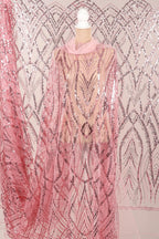 a mannequin wearing a pink sequin dress with a sheer overlay. The dress has a pink and silver sequin pattern, creating a visually striking and elegant design.