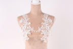 A mannequin with a white lace bodice and a white lace overlay, showcasing intricate floral patterns.