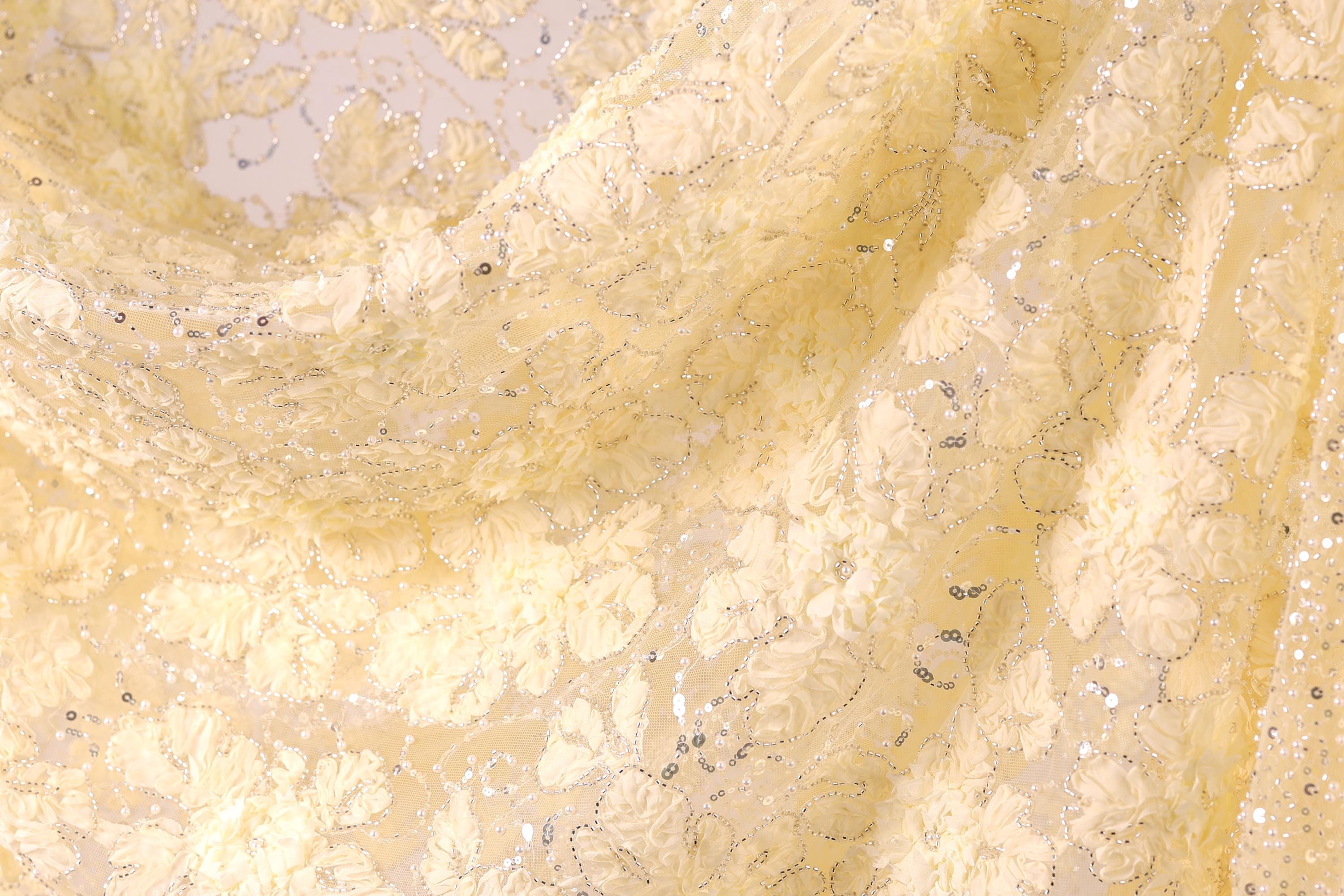 The image is a close-up of a fabric with a yellow floral pattern, featuring small white flowers and silver sequins.