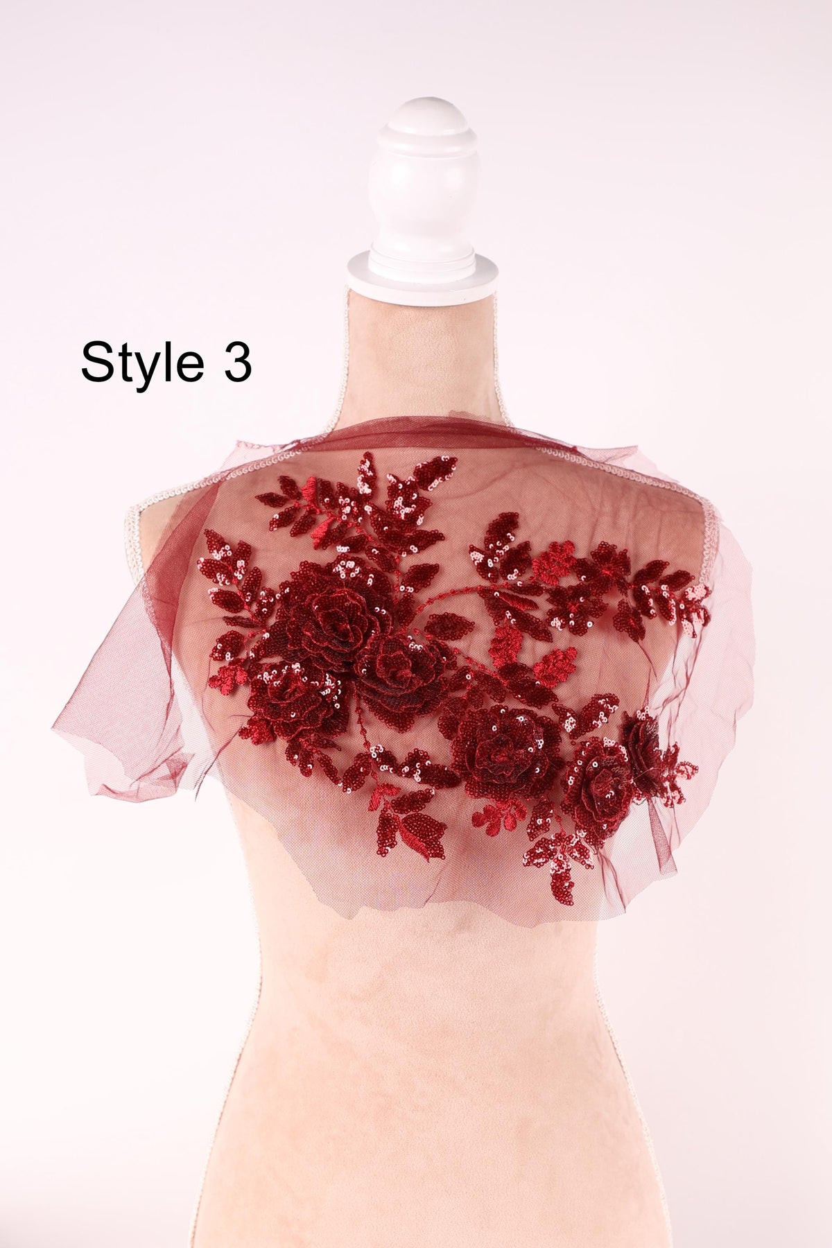 A mannequin wearing a red floral-patterned shawl or cape with a white headband.