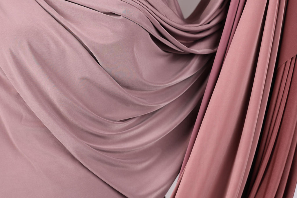 a close-up view of a fabric with a soft, flowing texture in shades of pink and red.