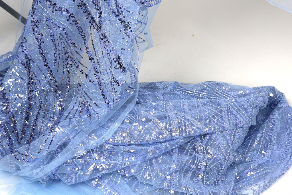 a close-up view of a piece of blue fabric with sequin details, possibly a dress or garment.