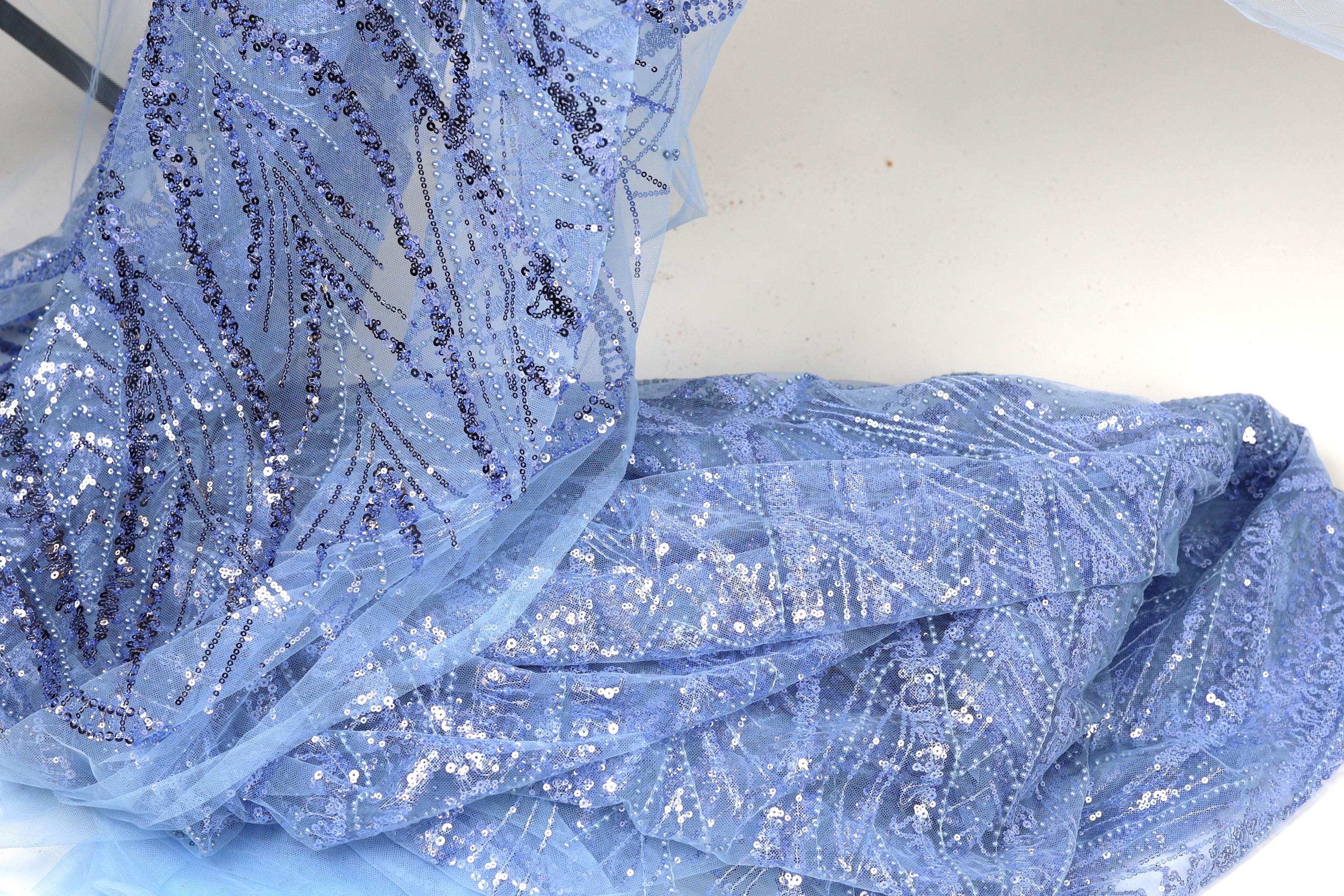 a close-up view of a piece of blue fabric with sequin details, possibly a dress or garment.