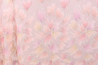 a close-up view of a fabric with a repeating pattern of pink and white flowers or leaves. The pattern is intricate and detailed, with the flowers or leaves appearing to overlap and create a sense of depth and movement. The fabric has a soft, delicate appearance, and the pink and white colors create a harmonious and visually appealing design.