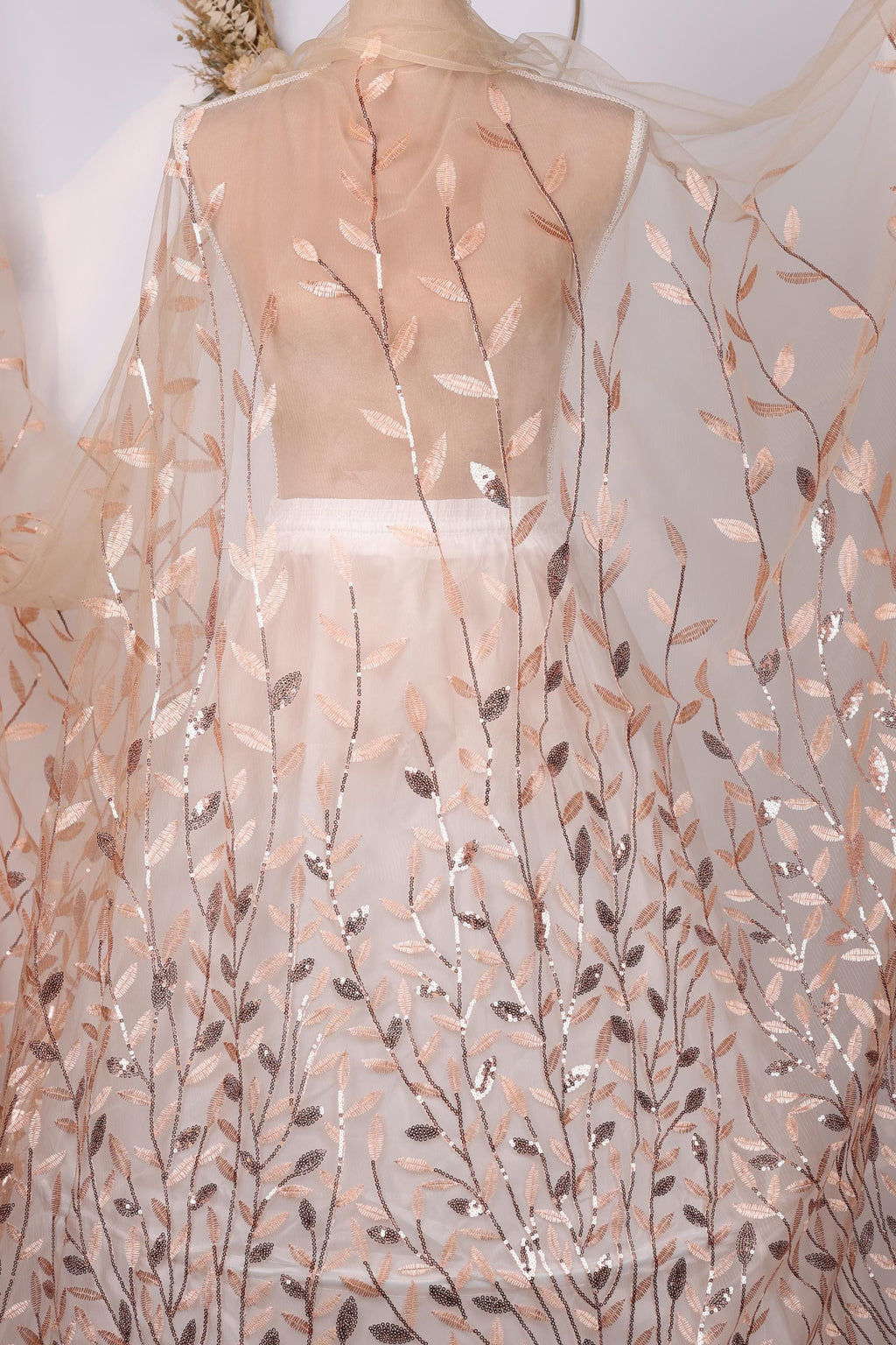 a sheer fabric with a leafy pattern, including various shades of brown and beige leaves. The fabric appears to be a sheer curtain or garment, with the leaves appearing to be embroidered or printed onto it.