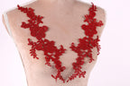 A mannequin wearing a red lace necktie with intricate floral patterns.