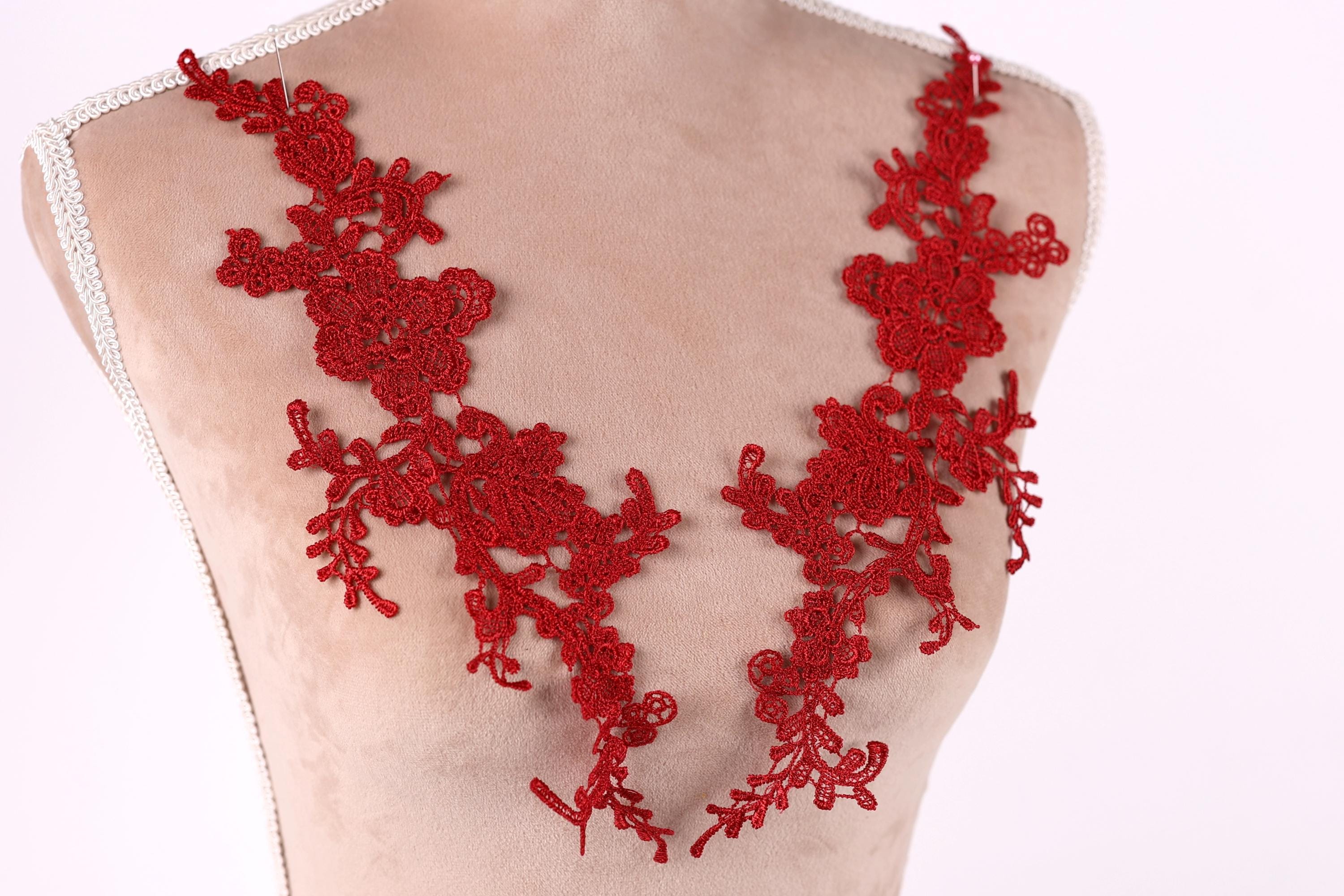 A mannequin wearing a red lace necktie with intricate floral patterns.