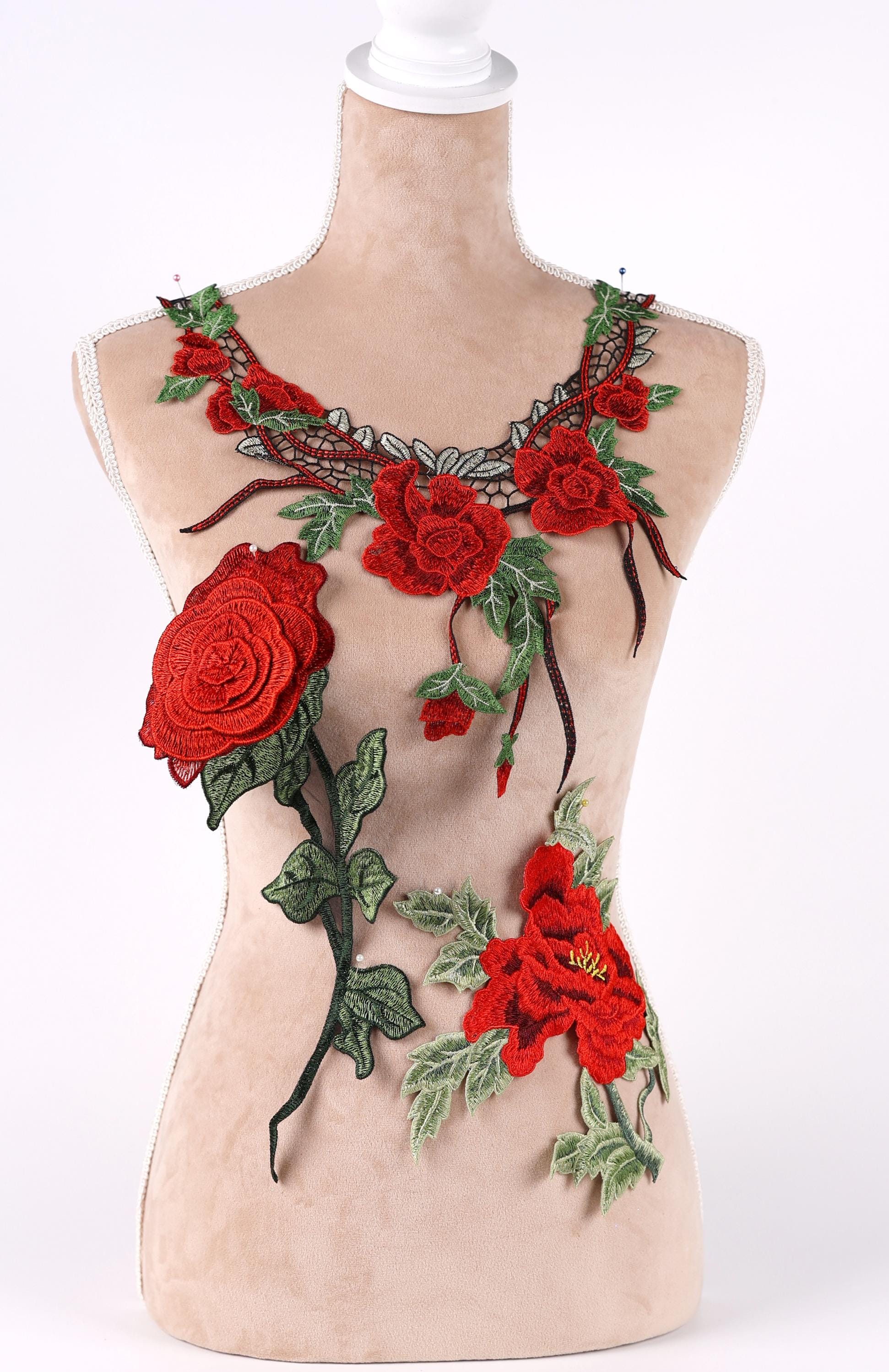A mannequin wearing a necklace with red rose embroidery and green leaves.