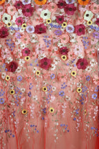 a vibrant and colorful floral pattern, with a variety of flowers in shades of pink, purple, yellow, and white. The flowers are intricately embroidered or sewn onto a fabric, creating a visually striking and detailed design.
