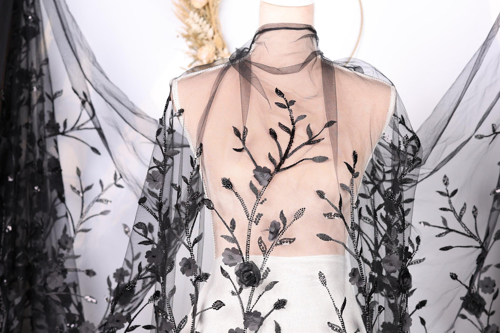 A mannequin wearing a sheer black dress with a floral pattern on the fabric.