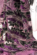 a close-up view of a fabric with a floral pattern in shades of purple and black, adorned with gold embellishments.