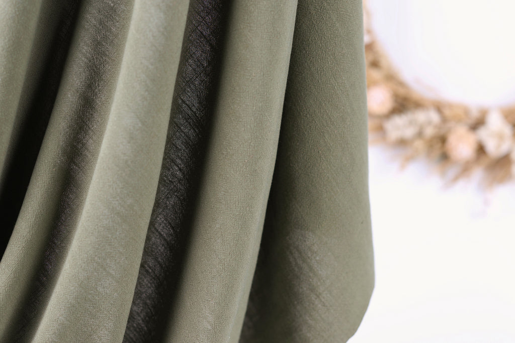 A close-up view of a fabric with a dark stripe running through it, against a blurred background.