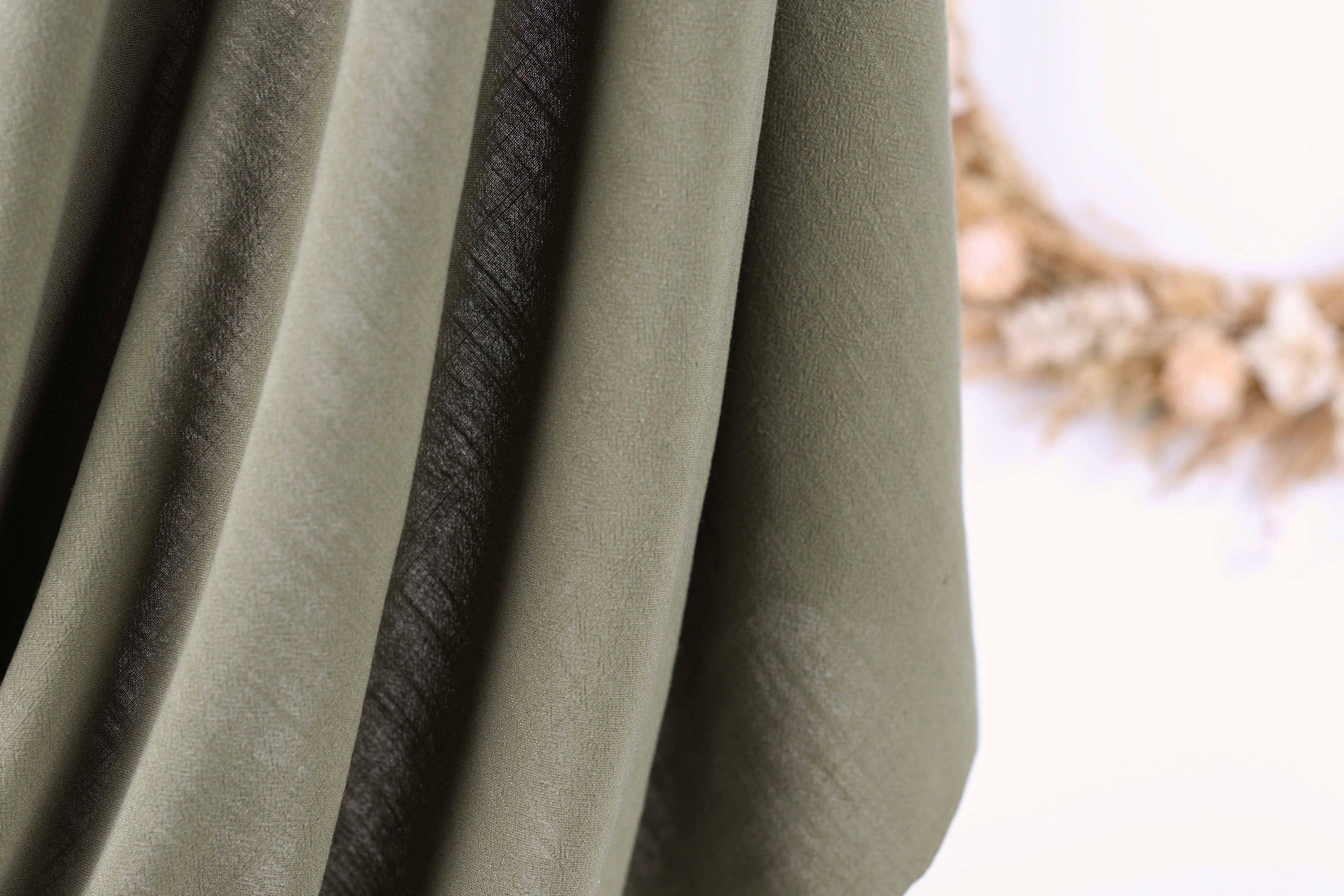 A close-up view of a fabric with a dark stripe running through it, against a blurred background.