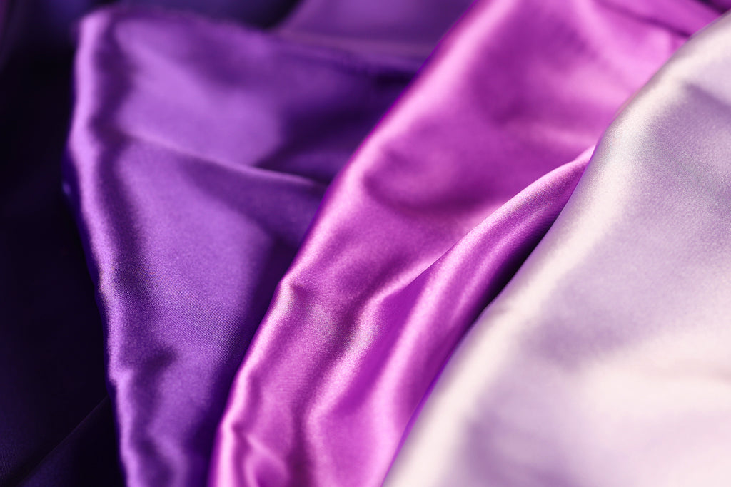 a close-up view of a fabric with a purple and white color scheme, with the purple fabric appearing more vibrant and the white fabric appearing more subdued.