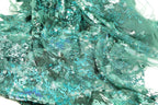 The image is a close-up view of a fabric with a green and blue color scheme, featuring a textured and patterned appearance.