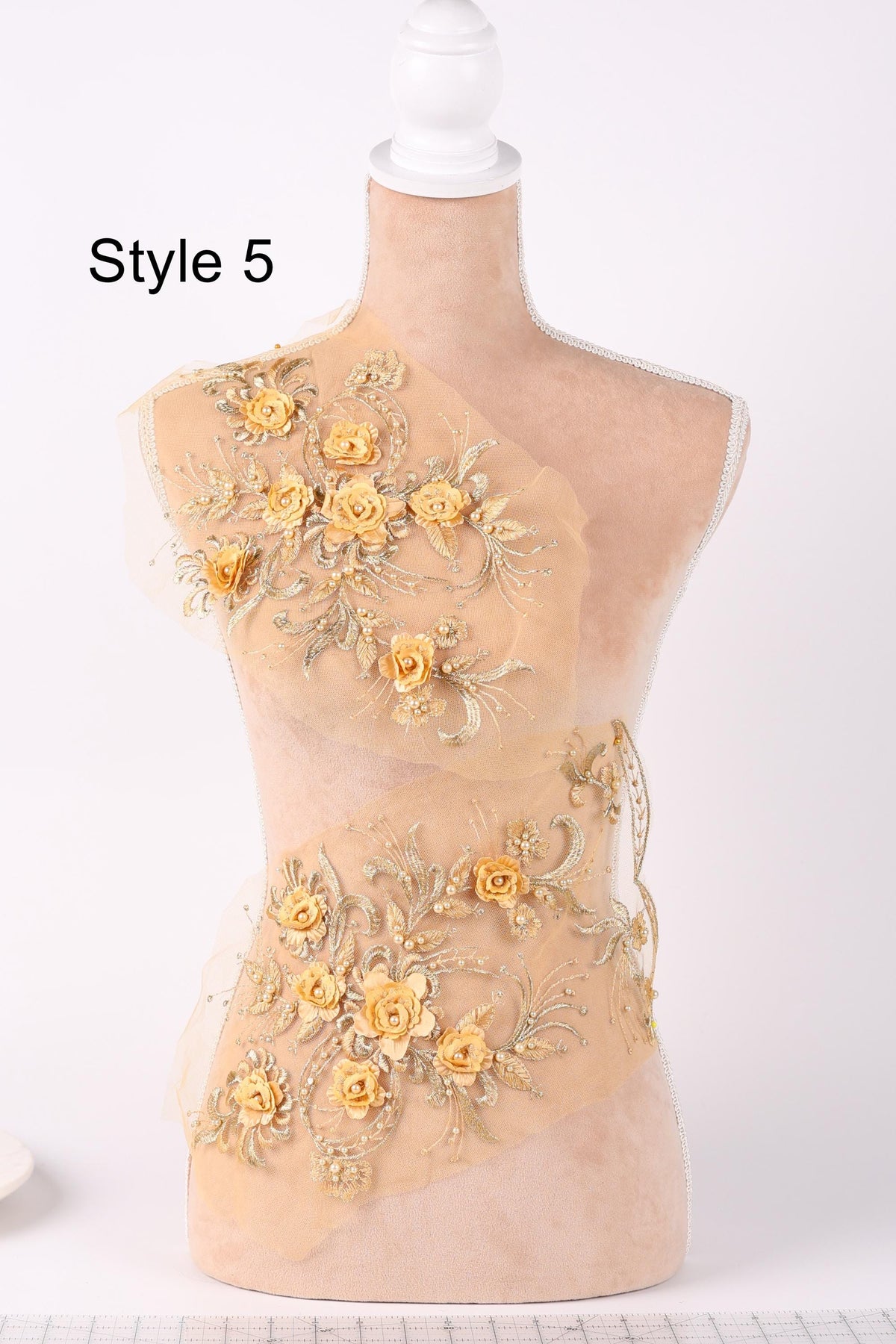 A mannequin with a beige body and a floral design on its torso, featuring yellow flowers and gold accents.