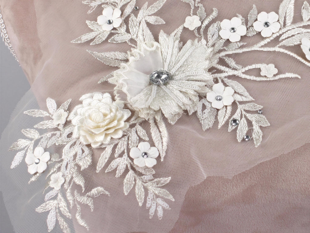 a close-up view of a delicate, intricate piece of lace or fabric adorned with white flowers and leaves, creating a beautiful and elegant floral design.