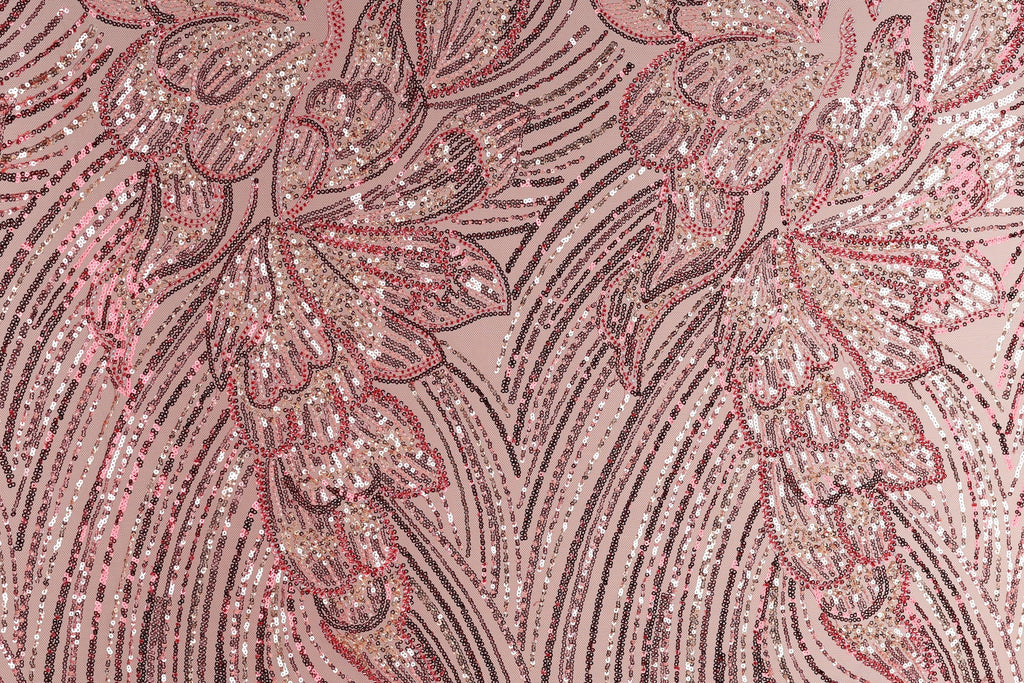 a close-up view of a fabric with a pink and red floral pattern, composed of numerous small sequins or beads arranged in a repeating, intricate design.