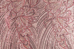 a close-up view of a fabric with a pink and red floral pattern, composed of numerous small sequins or beads arranged in a repeating, intricate design.