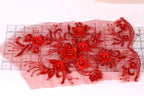 a close-up view of a red floral embroidery design on a white background. The design consists of numerous red flowers with intricate details, including petals and beads, arranged in a visually appealing manner. The flowers are spread across the image, creating a vibrant and eye-catching display.