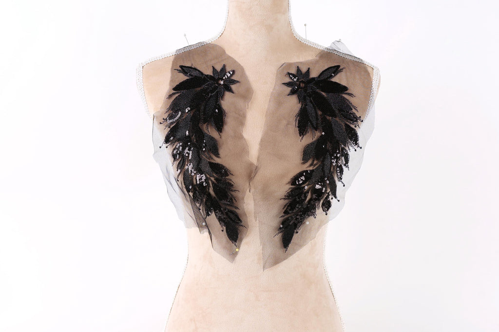 A mannequin with a beige body and black feather-like embellishments on the shoulders.