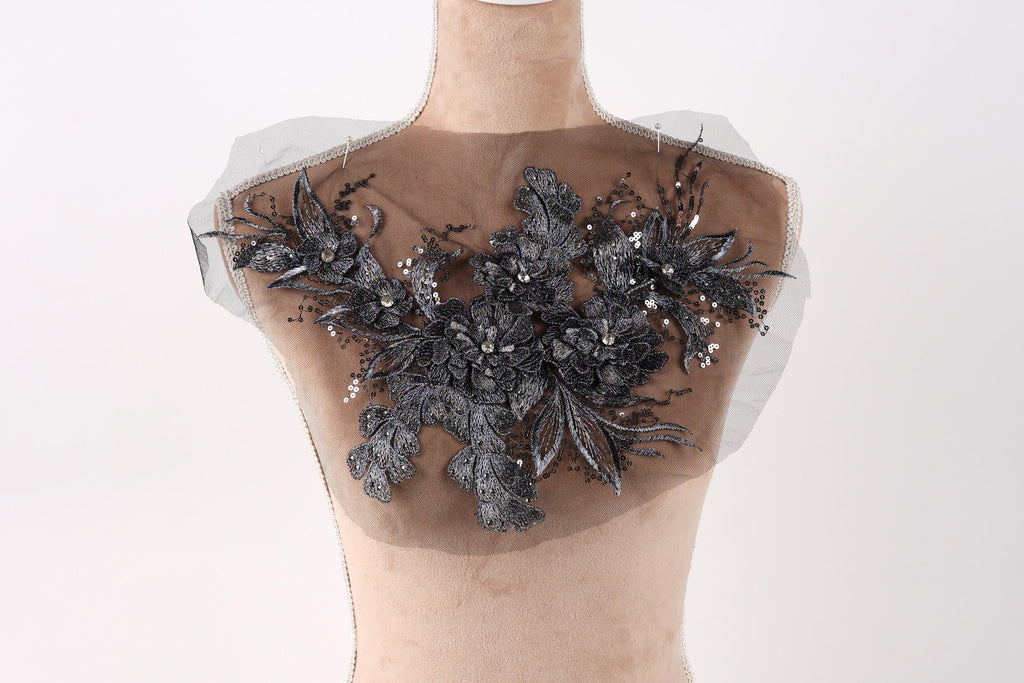 A mannequin with a decorative fabric piece on its chest, featuring a floral pattern with black and silver elements.