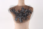 A mannequin with a decorative fabric piece on its chest, featuring a floral pattern with black and silver elements.