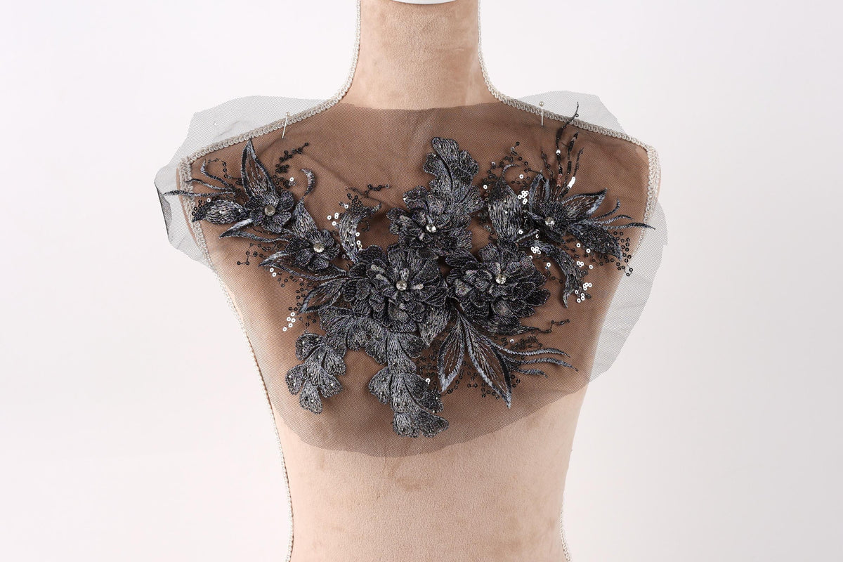 A mannequin with a decorative fabric piece on its chest, featuring a floral pattern with black and silver elements.