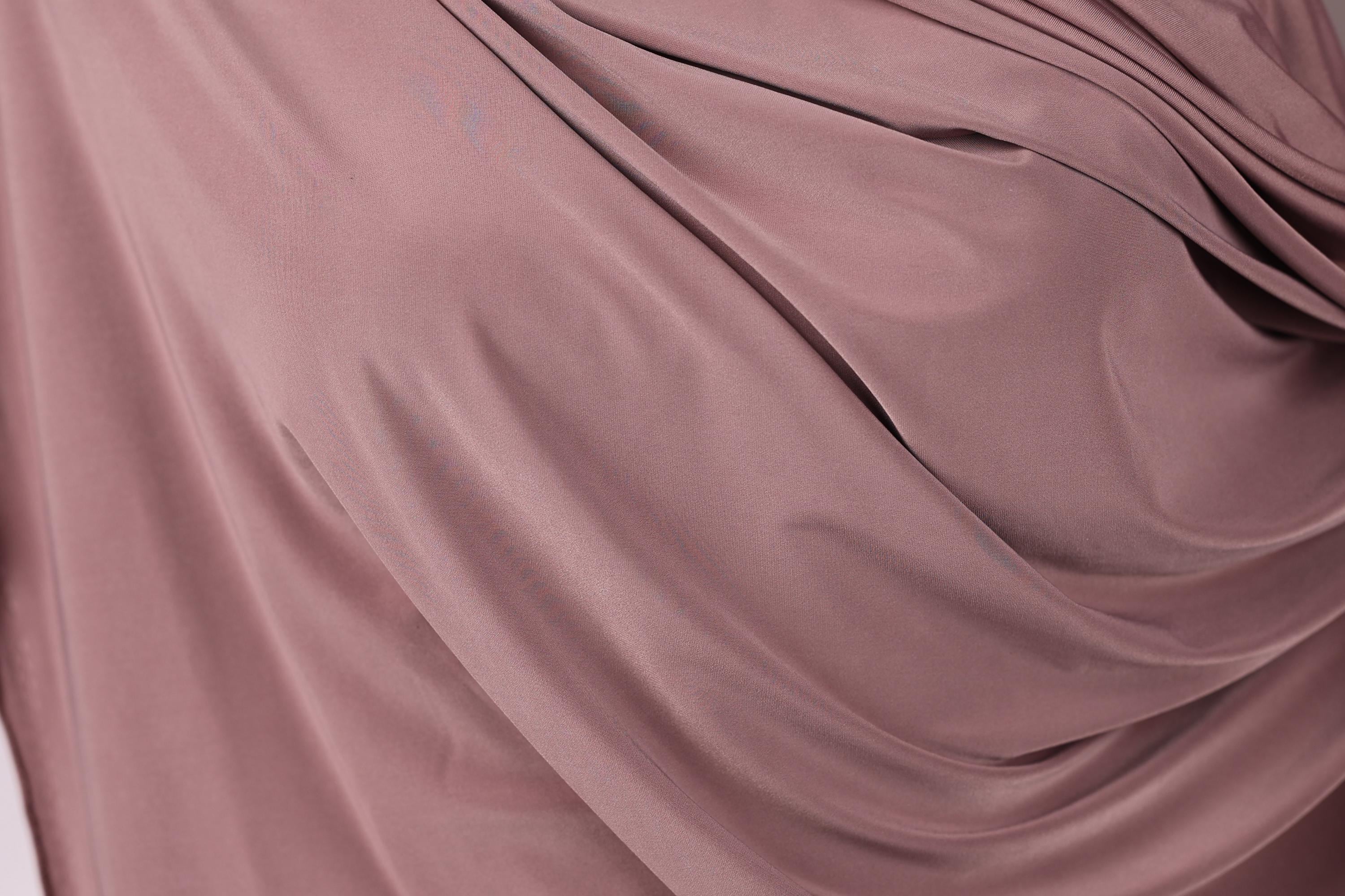 a close-up view of a soft, flowing fabric in a deep pink color. The fabric appears to be made of silk or a similar material, with a smooth and shiny texture. The fabric is draped or folded in a way that creates a sense of movement and softness.