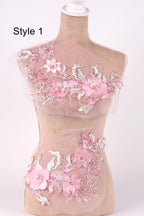 A mannequin wearing a pink floral dress with intricate lace and flower embroidery.