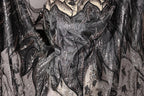 a close-up view of a black and silver fabric with intricate, sparkling designs. The fabric appears to be a sheer material, possibly lace or a similar type of textile. The design features a mix of black and silver elements, including sequins, beads, and floral patterns, creating a visually striking and detailed appearance.