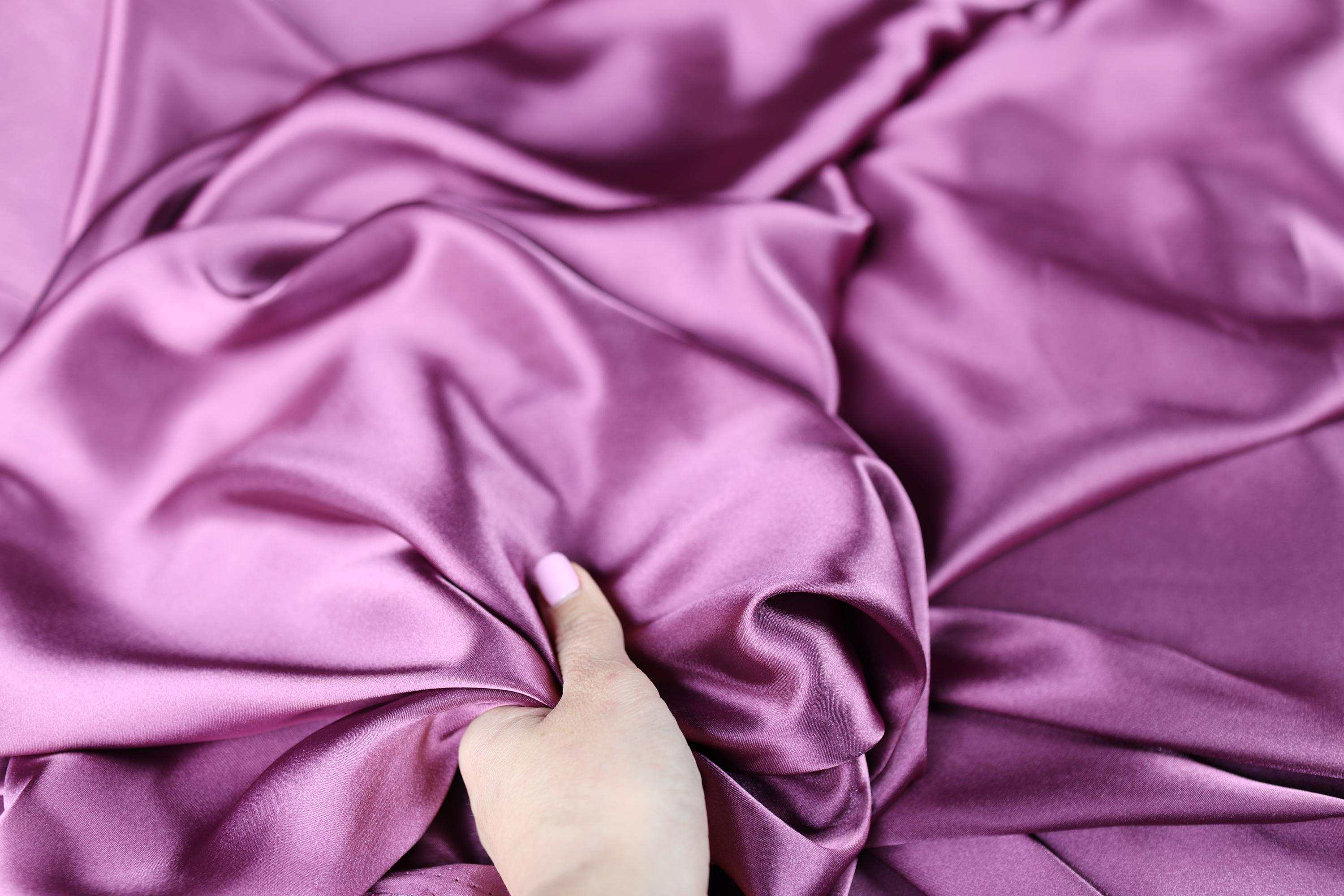 a person&#39;s hand on a purple cloth