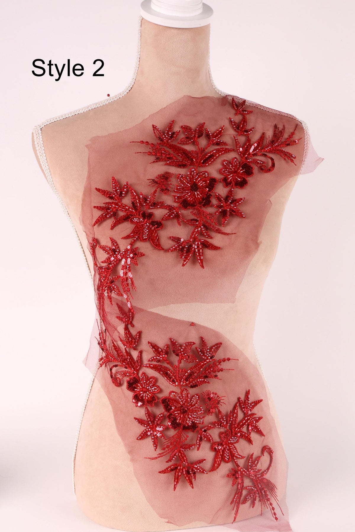 A mannequin with a red floral embroidered on its torso, featuring a variety of red flowers and leaves.