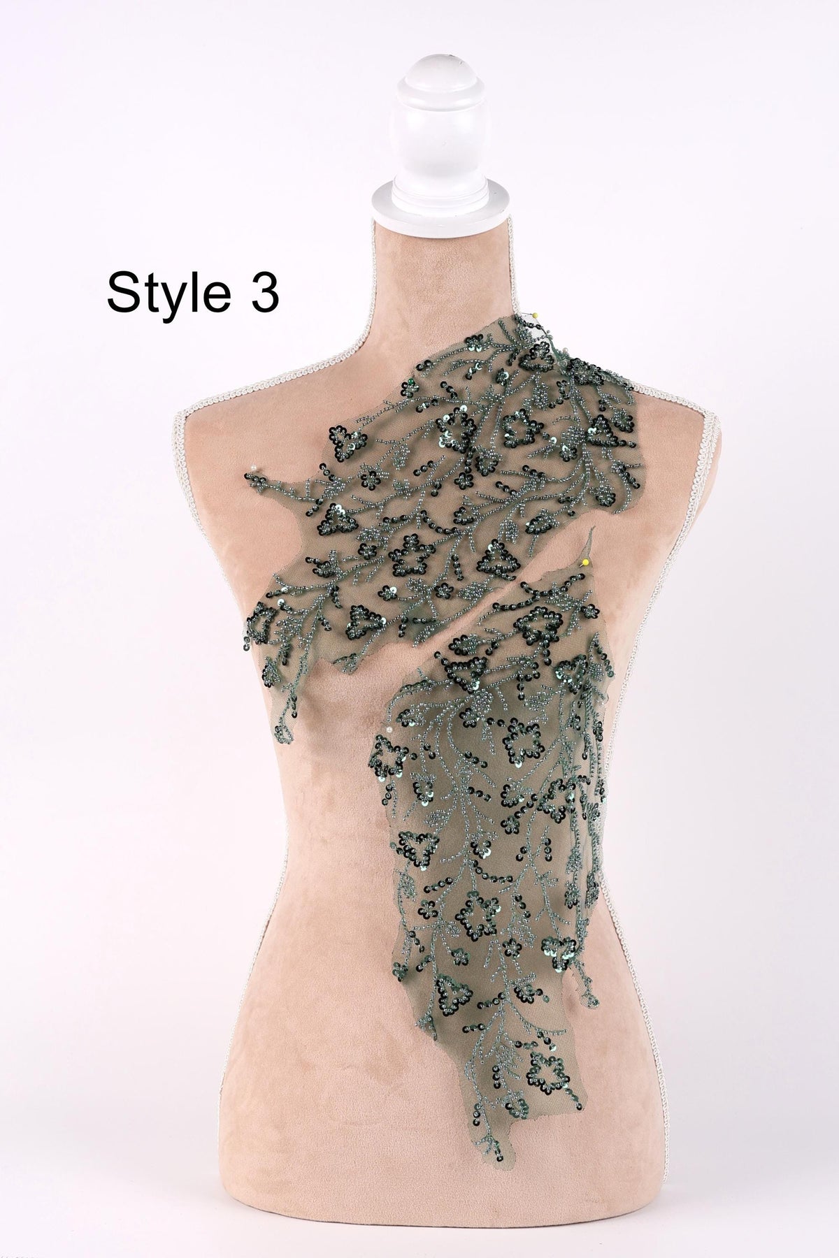 A mannequin with a beige body and a green floral pattern on the bust area, displayed against a white background.