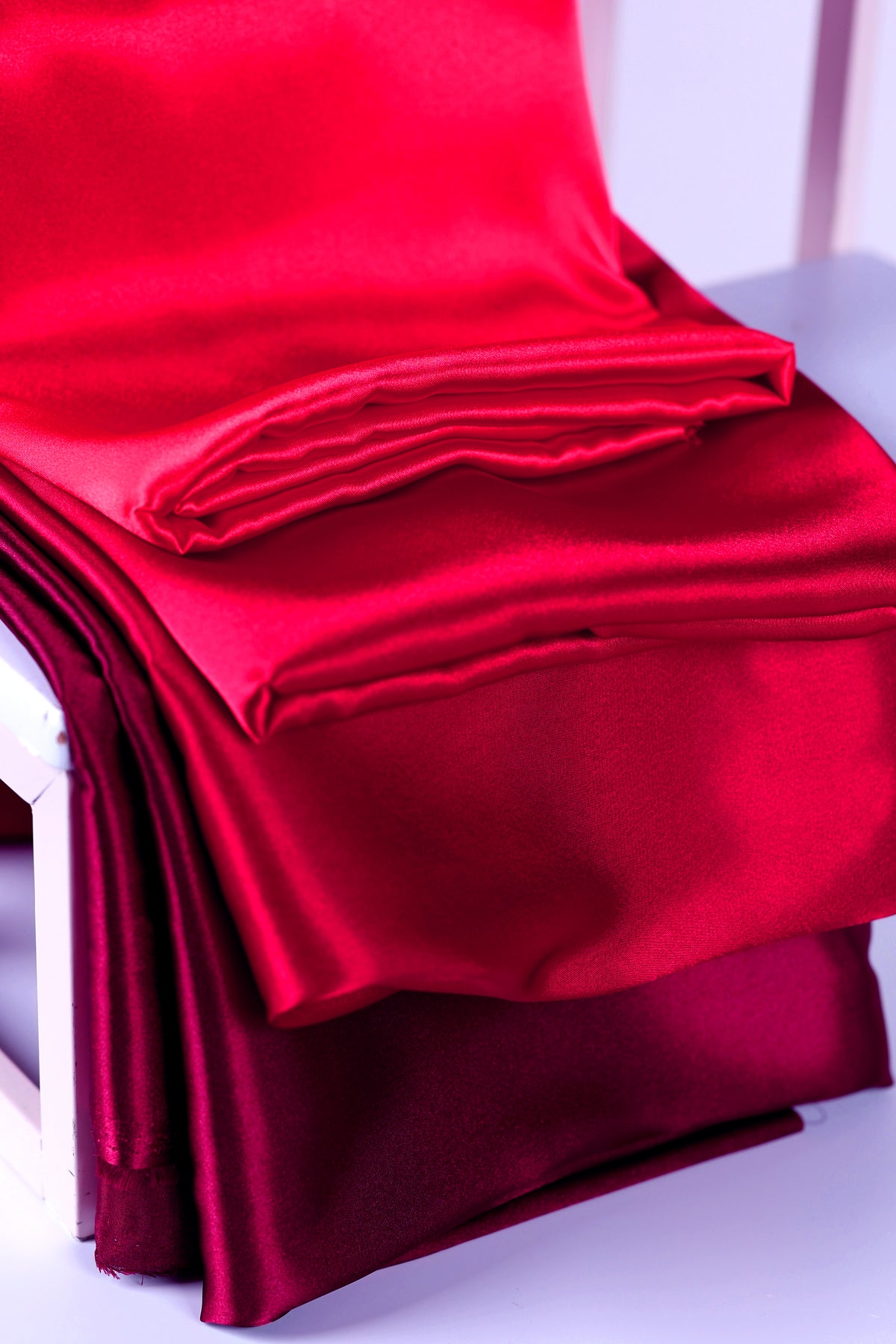 a close-up view of a red satin fabric, with a folded piece of the fabric visible.