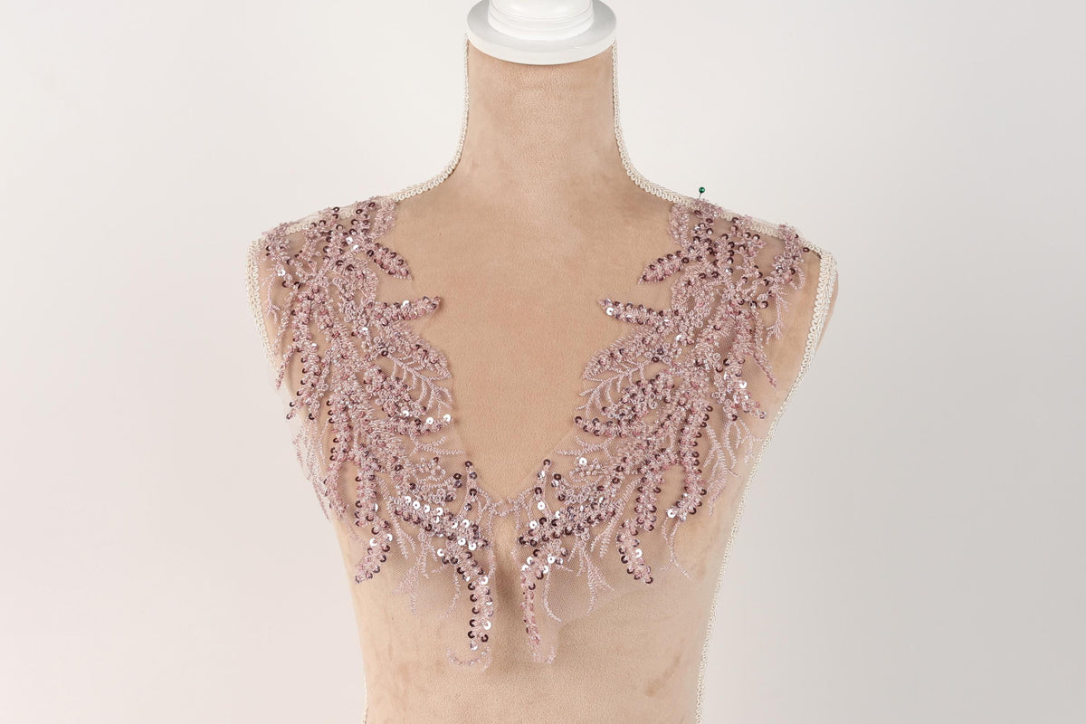 A mannequin wearing a pink sequin and lace neckline.