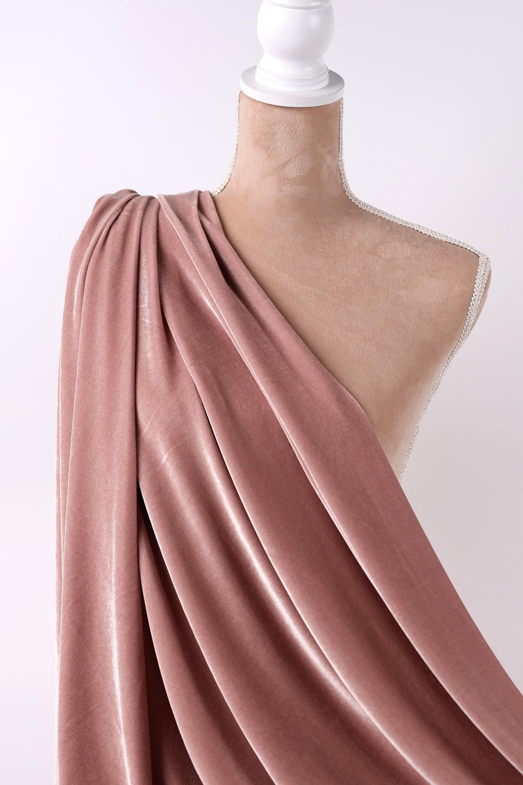 A mannequin wearing a pink velvet fabric draped over its shoulder.