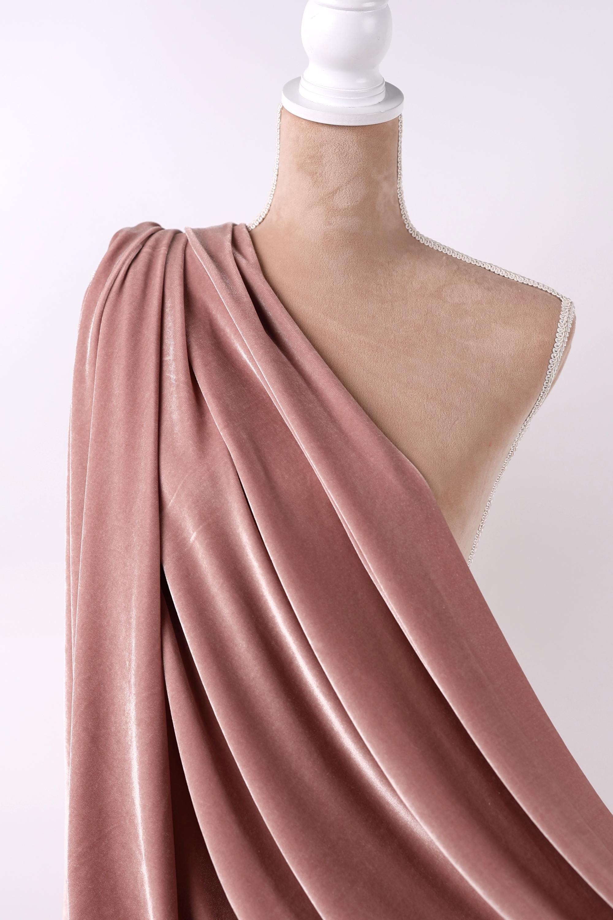 A mannequin wearing a pink velvet fabric draped over its shoulder.