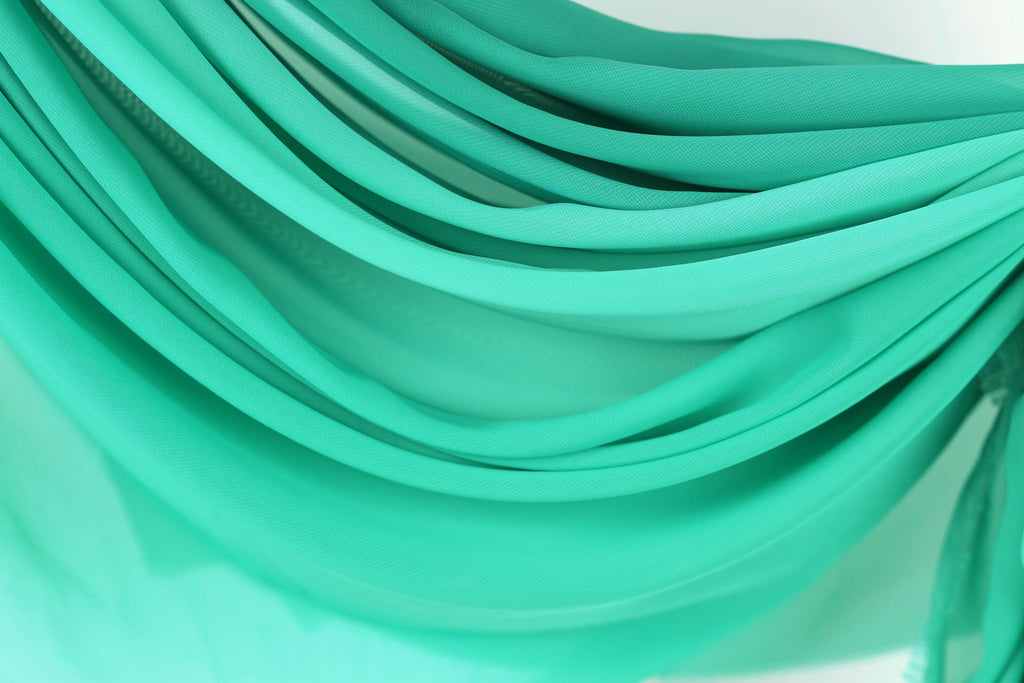 The image is a close-up of a fabric with a turquoise color, featuring a textured and layered appearance.