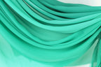 The image is a close-up of a fabric with a turquoise color, featuring a textured and layered appearance.